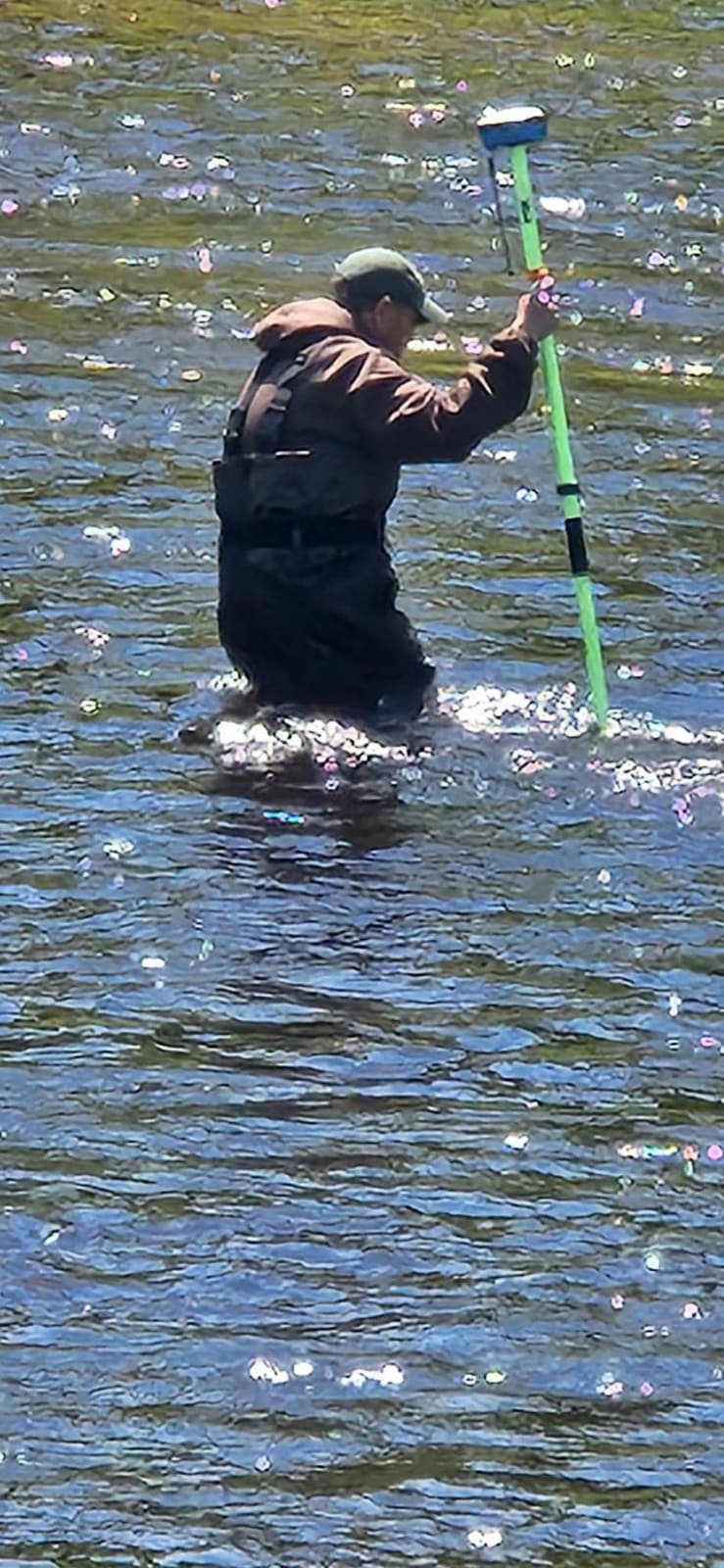 A surveyor collecting measurements while standing in a North Country river